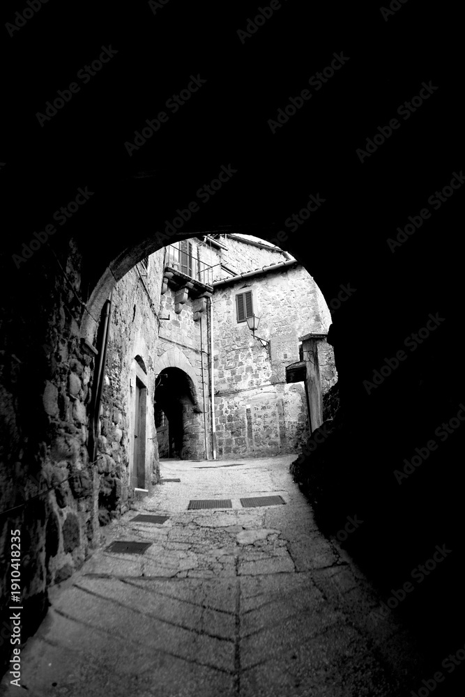 Obraz premium Borghi toscani in bianco e nero. L'architettura medievale dei borghi toscani, caratterizzata da pietra, cotto, riflette il periodo comunale con cinte murarie, torri, vicoli stretti e piazze. Italia. 