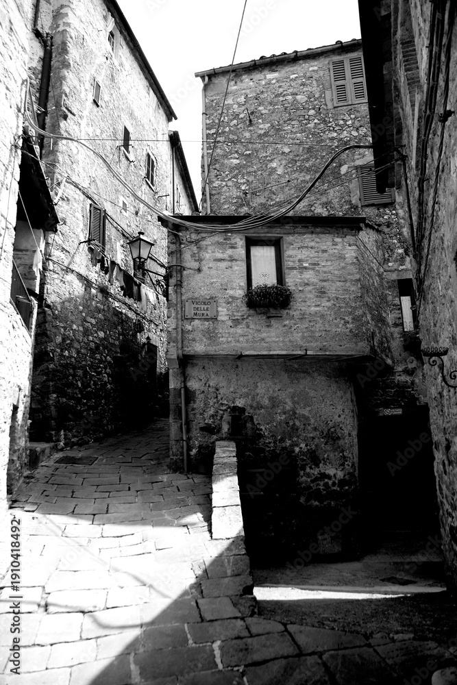 Obraz premium Borghi toscani in bianco e nero. L'architettura medievale dei borghi toscani, caratterizzata da pietra, cotto, riflette il periodo comunale con cinte murarie, torri, vicoli stretti e piazze. Italia. 