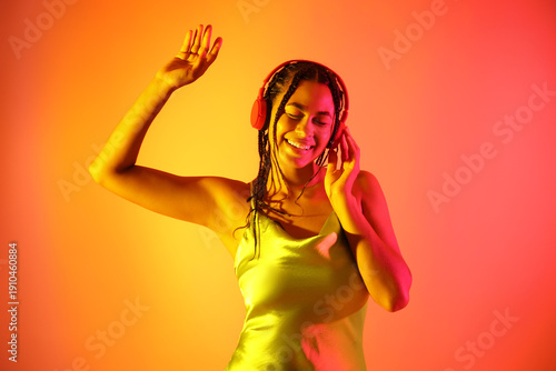 Young  African-American woman listening to music on color background