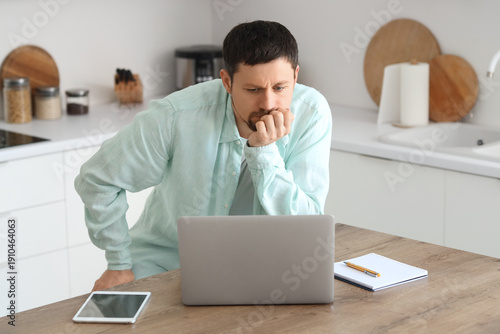 Confused young male teacher with laptop giving online lesson at home