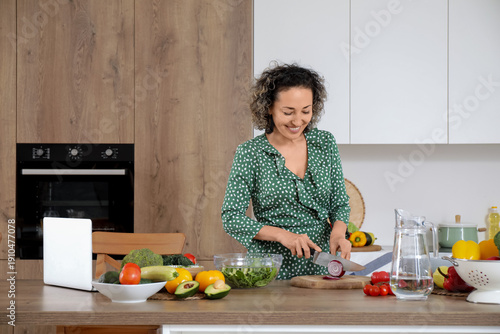 Mature woman cutting onion for salad in kitchen