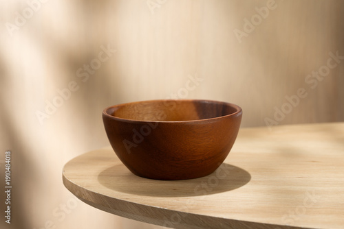 Empty Japanese style wooden bowl placed on a light round table with soft natural light. Minimal composition with clean background, ideal for food mockup or product display.