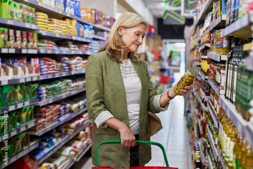 Senior woman checking information on a product label at supermarket