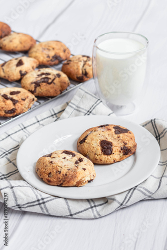 Homemade chocolate chip cookies with a glass of milk on a light background