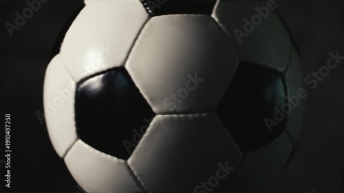 Seamless loop of a spinning soccer ball isolated on a dark background close up