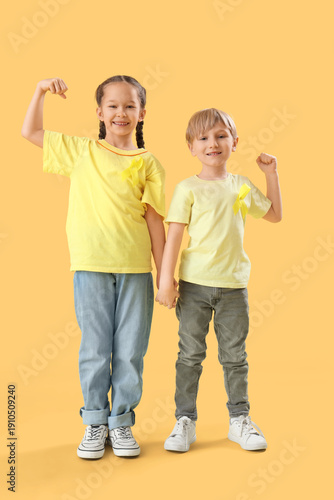 Cute little children with yellow ribbons showing muscles on color background....