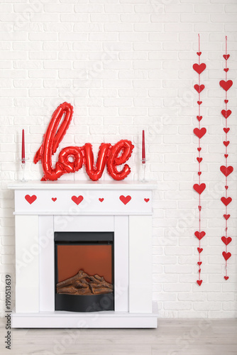 Fireplace with word LOVE made from balloons and heart-shaped garland in living room. Valentine's Day celebration