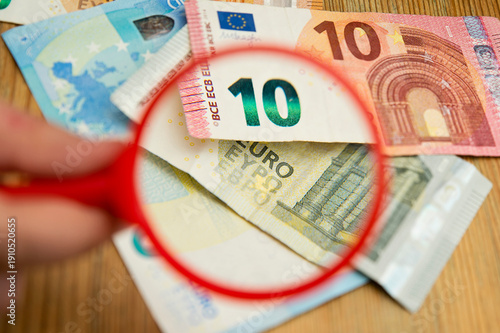 Euro banknotes under a magnifying glass. The concept of inflation, poverty, economic crisis. The concept of saving money. Finance, business, investment. Saving savings at home. 