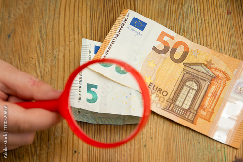 Euro banknotes under a magnifying glass. The concept of inflation, poverty, economic crisis. The concept of saving money. Finance, business, investment. Saving savings at home. 