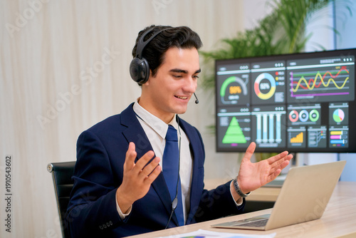 Businessman in navy suit wear headphone to conference meeting by laptop in conner of manager room.