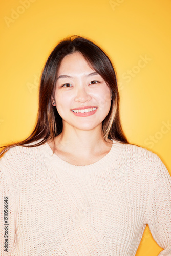 Portrait of beautiful young woman standing against yellow wall