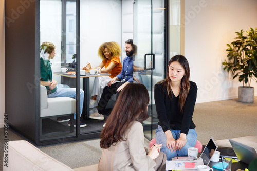 Wallpaper Mural Young female business expert listening to female manager explaining ideas while sitting in coworking office Torontodigital.ca