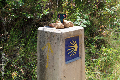 Camino sign with scallop in foreground and Monjardin hill with castle in background on Camino de Santiago Frances in Navarra Spain July 2024