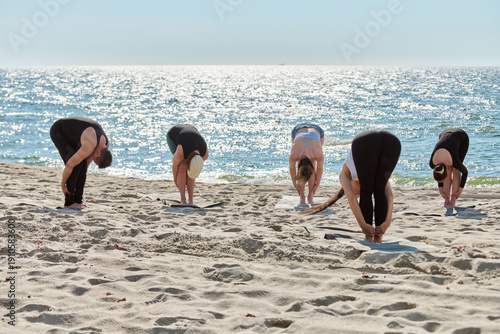 Wallpaper Mural Group yoga session with forward bend pose on Baltic Sea sandy beach Torontodigital.ca