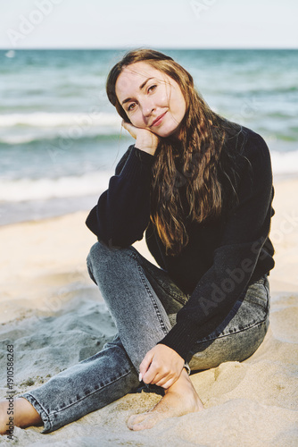 Wallpaper Mural Young woman with long brown hair sitting on sandy beach by calm sea Torontodigital.ca