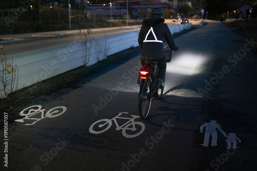 Woman cycling on illuminated bicycle lane in city at night