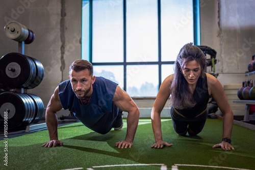 Determined athletes doing push-ups while working out in gym