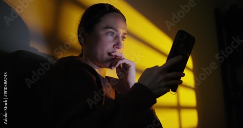 Anxious Woman Using a Smartphone at Night in a Dark Room
