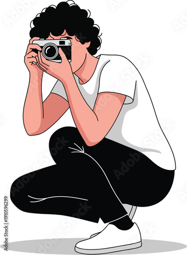 Crouching photographer with curly black hair holding a retro camera wearing a white tshirt and black pants.
