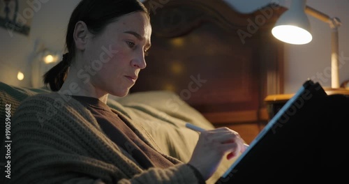 Focused Woman Drawing on a Digital Tablet in Her Bedroom at Night