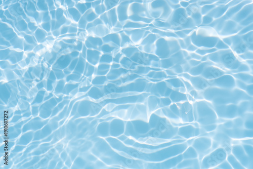 Blue water with ripples on the surface. Defocus blurred transparent blue colored clear calm water surface texture with splashes and bubbles. Water waves with shining pattern texture background.