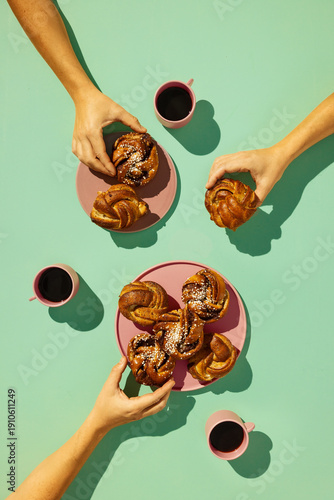 Top view of people sharing traditional Swedish cardamom and cinnamon buns with black coffee on a teal background. Modern, vibrant lifestyle photography of a Swedish fika moment.