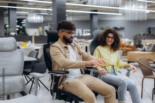 Couple shopping for ergonomic office chairs in furniture store