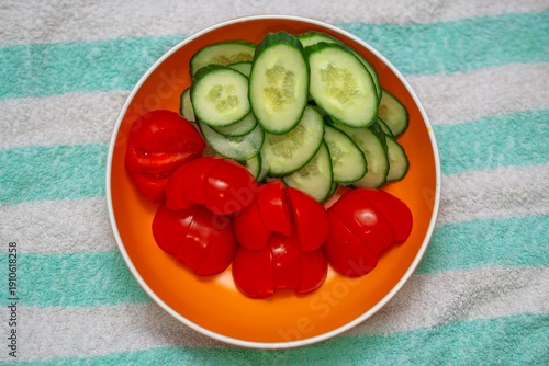Wallpaper Mural Sliced tomatoes and cucumbers in an orange plate on a white and green striped terry towel. Fresh vegetable arrangement Torontodigital.ca