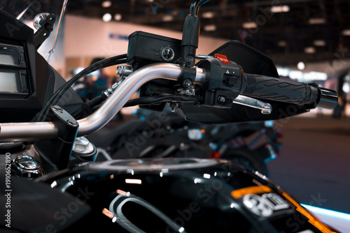 Motorcycle handlebar assembly with hydraulic lever, electrical controls, brake fluid reservoir, and textured grip.