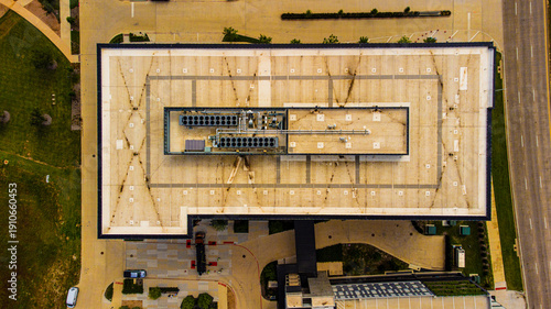 Aerial view of a building with a flat roof, surrounded by greenery and a road with cars, Plano, Texas, United States.