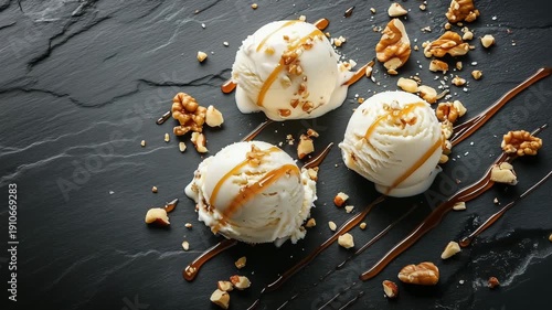 Ice cream scoops topped with nuts and caramel are arranged on a black marble surface