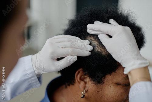 Vászonkép Middle aged Black woman sitting while healthcare professional wearing gloves exa