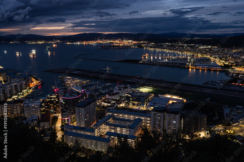 Fototapeta premium A stunning overhead perspective of Gibraltar's compact urban landscape, showcasing the seamless coexistence of sea traffic, air transport, and contemporary coastal development. Real estate market