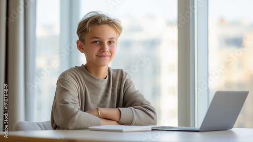 A young boy is sitting at a desk with a laptop and a notebook Free Download A young boy is sitting at a desk with a laptop and a notebook - GFXLoad