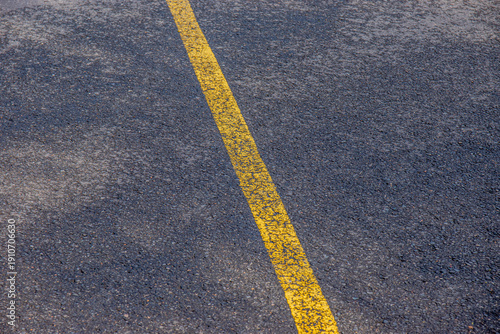 Focus sur une ligne jaune passée, tracée sur la route, format paysage