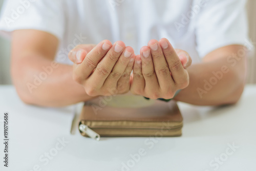 Concept of faith, peace, devotion, spiritual growth, and Islamic education during the holy month of Ramadan. Devout Muslim man praying dua during Ramadan month in bright indoor room
