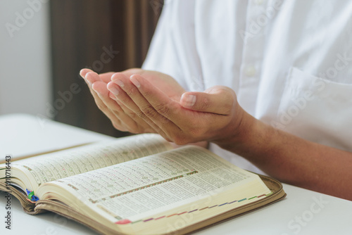 Devout Muslim man praying dua during Ramadan month in bright indoor room. Concept of faith, peace, devotion, spiritual growth, and Islamic education during the holy month of Ramadan