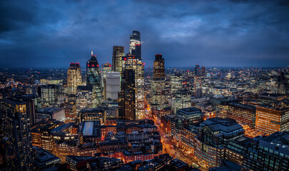Panoramic aerial view of the illuminated City of London skyline with office skyscrapers and street traffic at Bishopsgate during dusk