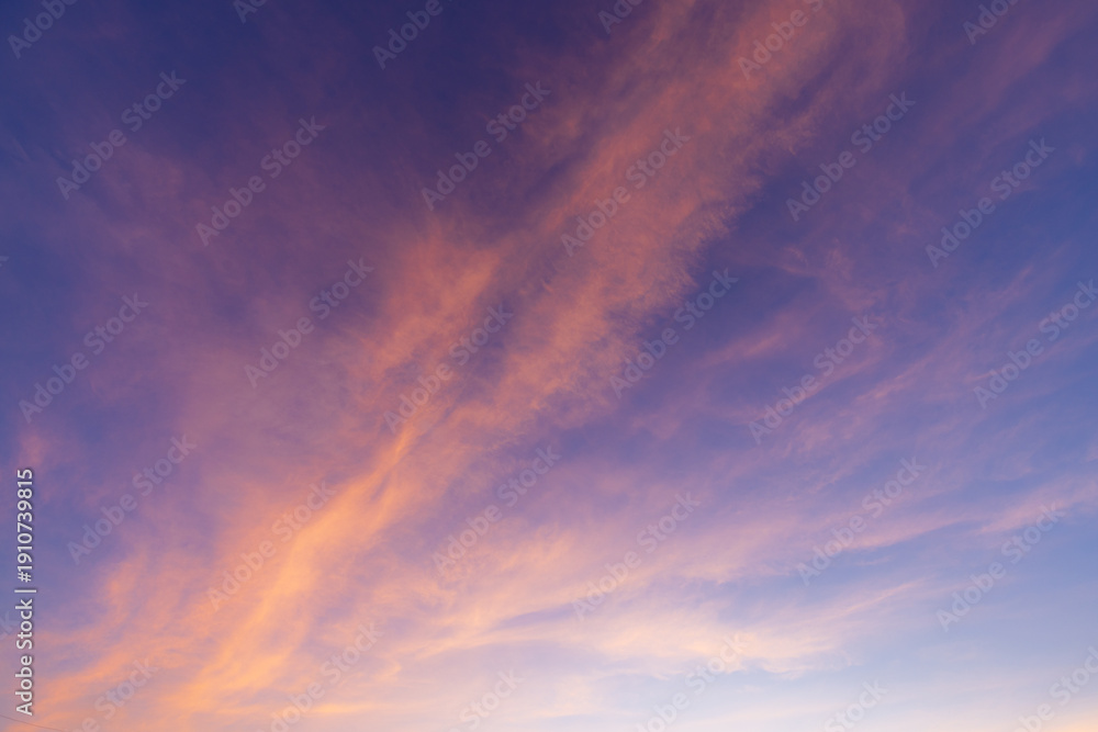 Fototapeta premium Dreamy Pastel Sunset Sky with Wispy Cirrus Clouds,A breathtaking view of a twilight sky filled with delicate, wispy cirrus clouds painted in shades of soft pink, orange, and deep purple.