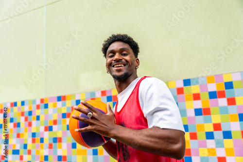 Smiling young man playing basketball on colorful court