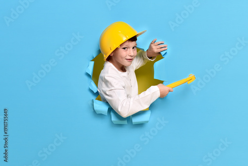 Boy builder wearing helmet. Concept of learning a profession. Child in workshop learning how to use hand tools. Tools for self-improvement. Inspector supervisor loves to work.