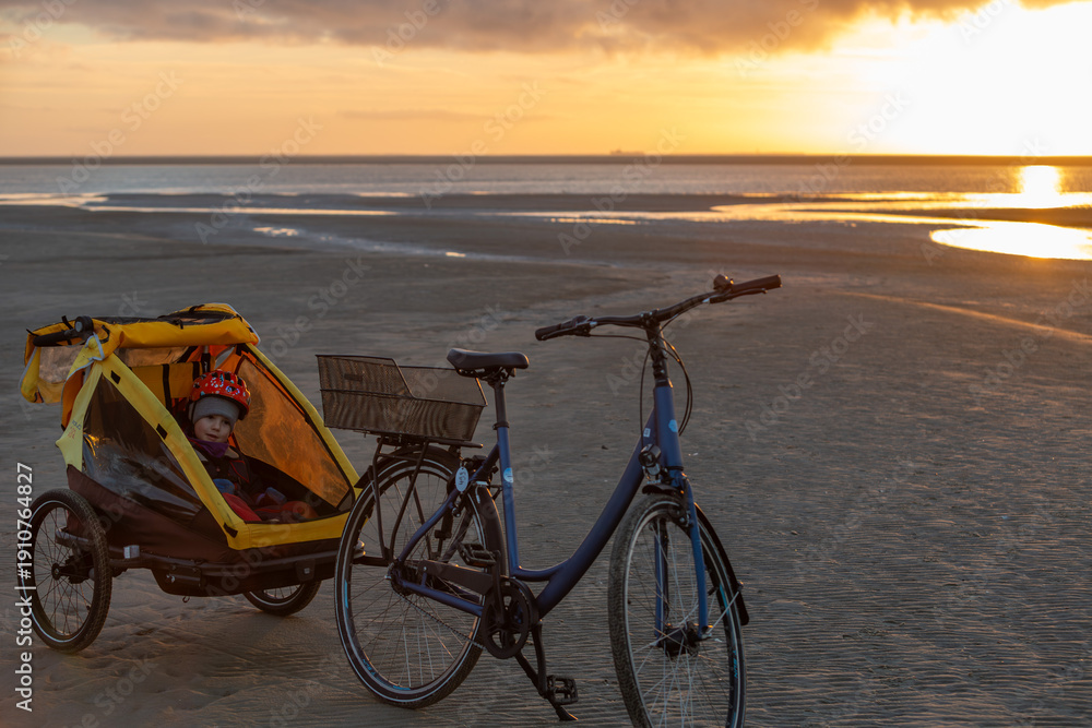 Fototapeta premium Fahrradtour an der Nordsee auf dem Strand, hier auf Borkum im Sonnenuntergang