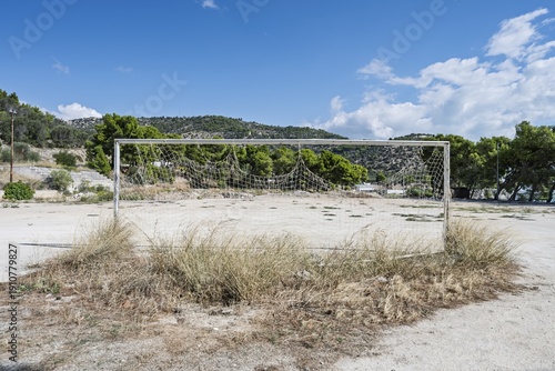 фотографія Old, dilapidated football goal on a neglected pitch, symbolizing mismanagement and depopulation in poorer Italian regions, weathered textures, overgrown grass, abandoned atmosphere