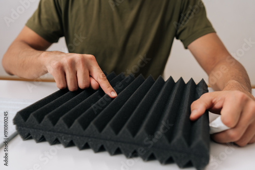 Person checking soundproof foam panel, doing quality check before installing acoustic insulation, preparing for diy project to improve audio quality and reduce noise for home recording, close-up.