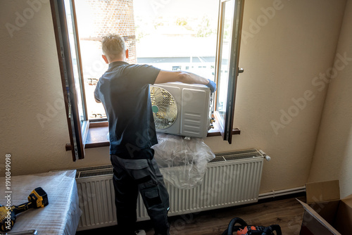 Master in black shirt is installing outer block air conditioner. Split system