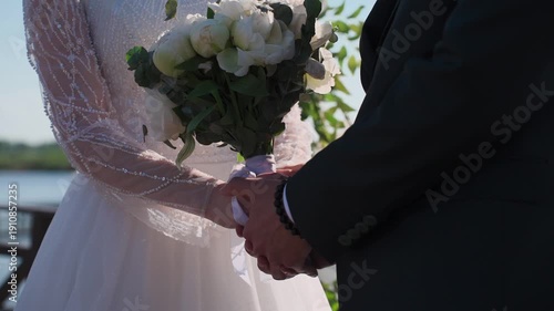 The groom tenderly embraces the bride with his arms on their wedding day