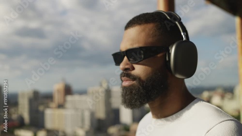 Wallpaper Mural Young African American male listening to music in headphones on rooftop, freedom Torontodigital.ca