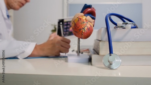 Schilderij op canvas Doctor examining heart anatomy model and medical data on a tablet, consulting ed