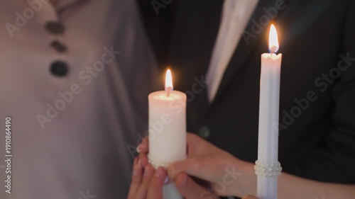 The newlyweds light the family hearth holding a candle in their hands