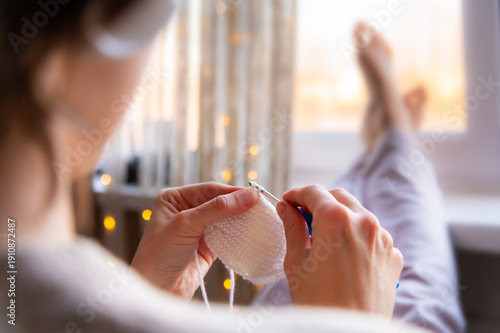 Foto A close-up of a young Caucasian woman's hands crocheting a woolen item at home